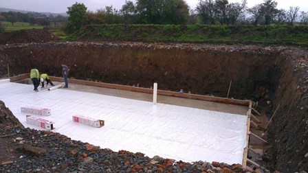 New build house & basement: membrane being rolled out onto basement slab, at Lisburn, Co. Antrim